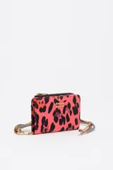 Billetera de tamaño mediano confeccionada en nylon, con cierre de cremallera y tirador de cordón. Presenta estampado animal print en tonos fucsia y negro, con logo metálico dorado en el frente.