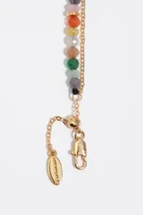 Pulsera doble de eslabones dorados combinada con cuentas de piedras multicolor y dije colgante en forma de corazón con logo grabado.