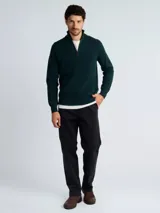 Sweater de punto color verde oscuro, con cuello alto y cierre frontal parcial, de manga larga y puños acanalados.