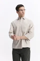 Camisa de popelina a cuadros, color celeste y blanco, de manga larga y corte holgado. Presenta un bolsillo frontal y cartera abotonada.