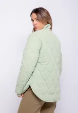 Campera puffer color crudo con diseño matelaseado de curvas, cuello alto, cierre metálico frontal, dos bolsillos dobles y puños con elástico.