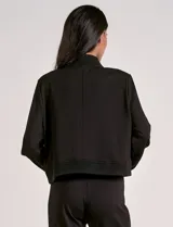 Camperita tipo bomber color beige claro, con cuello redondo acanalado, cierre frontal con broches metálicos y bolsillos delanteros con tapa. Los puños y el bajo son acanalados.