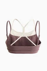 Top deportivo color malva con forro interior en tono crudo, confeccionado en tejido funcional con diseño de doble bretel fino en contraste y copas con relleno extraíble.