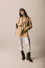 Blazer de cuero color celeste metalizado, con solapas, cierre con broches tipo tanca de madera y puños con detalle de piel sintética marrón.