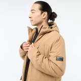 Parka ligera color beige con capucha ajustable, cierre frontal con cremallera y parche decorativo con texto en la manga.