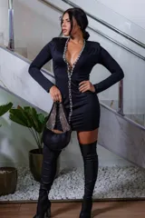 Minivestido negro de manga larga con profundo escote en V bordeado de pedrería y detalles de cadenas de strass, con hombreras estructuradas y corte ajustado al cuerpo.