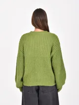 Buzo de tejido de punto grueso en color verde, con cuello redondo, mangas largas y corte holgado.