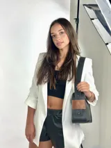 Bolso baguette de cuero negro con asa reversible y logo de la marca en etiqueta de cuero marrón.