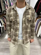 Sobrecamisa de paño con diseño a cuadros en tonos tostado y beige, corte recto, cuello clásico, cierre frontal con botones y dos bolsillos delanteros con solapa y botón.
