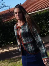 Saco abrigado de tejido texturizado en tonos marrones y negros, con diseño a cuadros, ribetes de lino en los bordes y cierre frontal con lazos.
