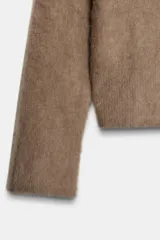 Jersey de punto con textura efecto cepillado, cuello en V y manga larga con terminaciones en rib.