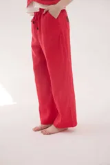 Pantalón de lino color beige, de silueta relajada, tiro medio-alto, cintura elastizada con cordón ajustable, bolsillos laterales y bolsillos traseros.