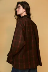 Chaqueta de mujer de la colección Zara Woman, confeccionada en algodón 100% con acabado encerado. Presenta un estampado a cuadros en tonos marrón y rojo, cuello solapa de pana, manga larga con puño y botón, bolsillos de plastrón con solapa en el delantero y cierre frontal con botones a presión.