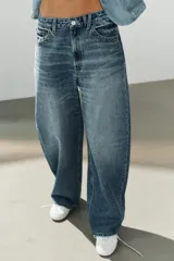 Jeans de tiro medio con diseño baggy, de pernera ancha y corte holgado. Cuenta con cinco bolsillos, trabillas para cinto y cierre frontal con cremallera y botón metálico.