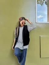 Remerón de manga larga con diseño de rayas horizontales finas en color negro sobre fondo blanco. Presenta un corte oversize, cuello redondo y un largo asimétrico con la parte trasera ligeramente más larga que la delantera.