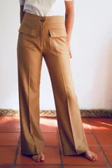 Pantalón de vestir color camel, de paño de lana, corte recto y tiro alto, con bolsillos delanteros tipo parche con solapa y botón.
