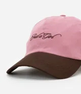 Gorra rosa con visera marrón, confeccionada en sarga de algodón, con bordado frontal con la frase "Just a Girl" en color marrón.