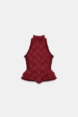 Corset bordó de cuello halter con hombros descubiertos, confeccionado con combinación de tejidos con patrón floral, detalles de volados en las sisas y bajo en peplum. Cuenta con cierre en la espalda con cremallera.