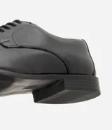Zapato masculino formal de poliuretano color negro, diseño clásico con cordones y puntera alargada.