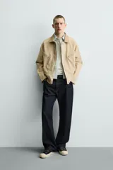 Cazadora relaxed fit de Zara confeccionada en denim de algodón color beige, con cuello de solapa en piel combinada, bolsillos con cremallera en el pecho y cierre frontal oculto.