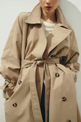 Gabardina midi de doble botonadura con diseño oversized, solapas de muesca, cierre frontal con botones y cinturón extraíble para atar en la cintura. Presenta mangas raglán con trabillas ajustables en los puños, bolsillos laterales y abertura posterior.