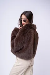 Chaqueta de piel sintética en color marrón, con cierre frontal y diseño de corte corto y voluminoso.