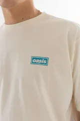 Remera color crudo de algodón con estampado azul de la banda Oasis, con logo, dibujos de los integrantes y referencias a sus canciones.