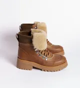 Borcegos de cuero vacuno en tonos marrón, con diseño de caña media y cuello con forro de piel sintética negra. Presentan cordones marrones, ganchos metálicos para ajuste y suela de goma tipo track con plataforma.