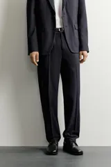 Pantalón de traje relaxed fit color negro, confeccionado en tejido con lana, con bolsillos frontales, bolsillos traseros de doble vivo con botón y raya marcada en las piernas.