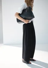 Pantalón wide leg de tiro medio color negro, con diseño largo, bolsillos laterales, bolsillos de ribete posteriores y detalle de pinzas. Cuenta con cierre oculto de botón, gancho y cremallera, e incluye forro interior.