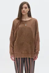 Buzo de corte oversize con cuello redondo y mangas largas de hombros caídos. Presenta un acabado lavado y un pequeño bordado en el frente.