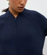 Campera deportiva de cuello alto con cierre frontal, mangas largas con puños elásticos y diseño de corte raglán. Presenta un estilo minimalista y funcional con cintura ajustable.