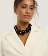 Collar maxi de esferas grandes de resina negra combinadas con pequeñas cuentas doradas.