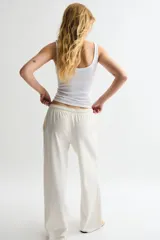 Pantalón de jogging color crudo, de corte amplio, con cintura elástica ajustable con cordón y bolsillos laterales.