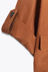 Chaqueta corta de escote en pico con cierre frontal de un botón. Presenta mangas cortas con detalle de vuelta, trabilla y botón, además de falsos bolsillos delanteros con solapa.