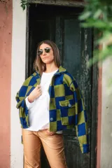 Sobre camisa de paño con diseño a cuadros en tonos azul y verde, cuello clásico, cierre frontal con botones y bolsillos grandes frontales.