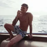 Short de baño con estampado abstracto en tonos celestes y azules. Cuenta con pretina fija, hebillas metálicas laterales para ajuste, cierre frontal con botón a presión y tres bolsillos.