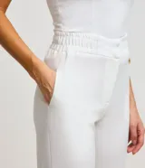 Pantalón de vestir blanco, modelo carrot, con cintura elástica en la espalda, cierre por cremallera y botón, detalle fruncido en el bajo y bolsillos laterales.