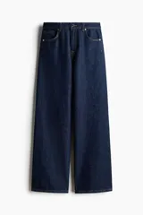 Jean de tiro alto confeccionado en denim de algodón lavado, con diseño de cinco bolsillos y piernas rectas de corte holgado. Cierre frontal con botón y cremallera.