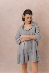 Vestido camisero corto de denim liviano azul con efecto desgastado, de corte oversize, con cuello camisero, botonadura frontal, bolsillo plaqué en el pecho, mangas largas y volado fruncido en el ruedo.