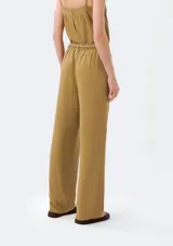 Pantalón de corte recto color beige con pinzas en la parte delantera y tira ajustable a modo de cinturón con nudos decorativos.