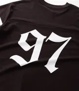 Remera deportiva de algodón color marrón con cuello en V y mangas cortas. Diseño overboxy con estampado de fútbol americano, lettering y rayas contrastantes en blanco.
