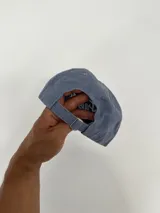 Gorro tipo jockey color azul, con visera curva y bordado frontal que dice "Faded" en blanco y "Sunset Flower Faded Sense Again" en naranja.