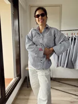 Camisa oversize a rayas verticales blancas y negras con bordado rojo en el frente.