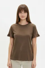 Remera blanca de algodón, de corte ajustado, con cuello redondo y mangas cortas terminadas con volados delicados.