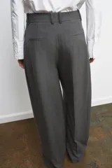 Pantalón de tiro medio con pinzas frontales, confeccionado en tejido con viscosa. Presenta cintura con trabillas, bolsillos laterales y cierre frontal con cremallera, botón y ganchos metálicos.