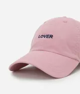 Gorra tipo bucket de sarga color rosa pálido, con visera curva y la palabra "Lover" bordada en negro en la parte frontal.