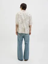 Camisa de manga corta con cuello resort, confeccionada en una mezcla de algodón y lino. Presenta un diseño estampado con motivos tipo damasco en tonos neutros y un corte amplio.
