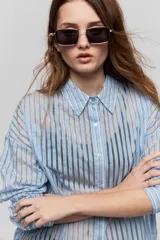 Camisa de rayas de calce relajado, confeccionada en tejido liviano y semitransparente, con cuello clásico, cierre frontal con botones, mangas largas con puños y hombros caídos.