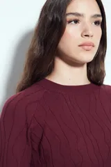 Sweater de punto color negro, con cuello redondo y diseño texturizado con ondas en relieve. Presenta mangas largas y un calce cómodo y holgado.